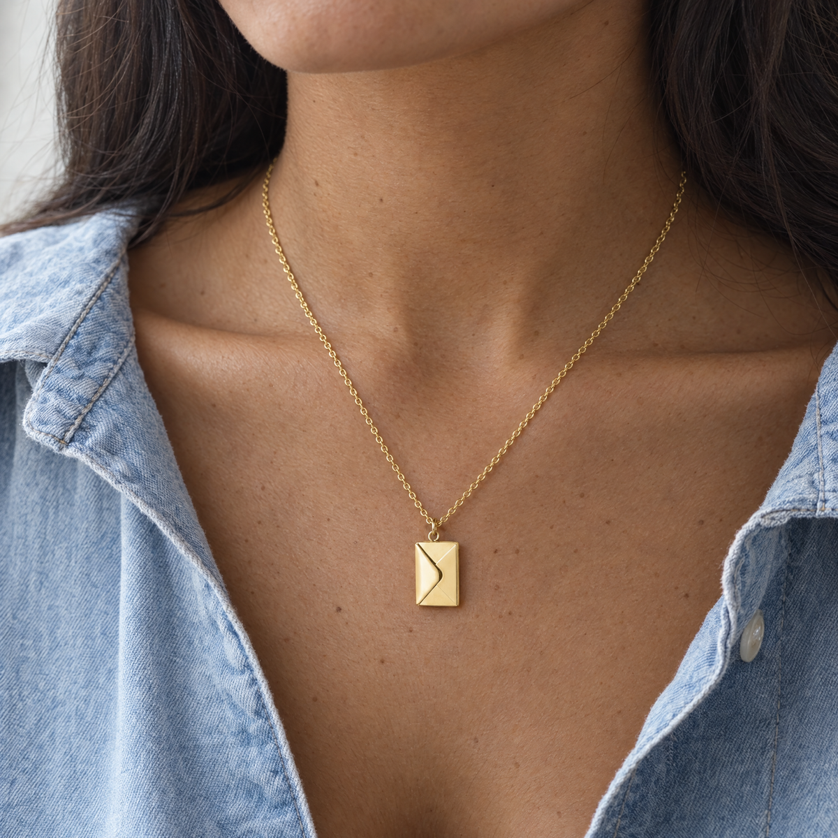 Cuello de una mujer con el colgante de sobre dorado cerrado