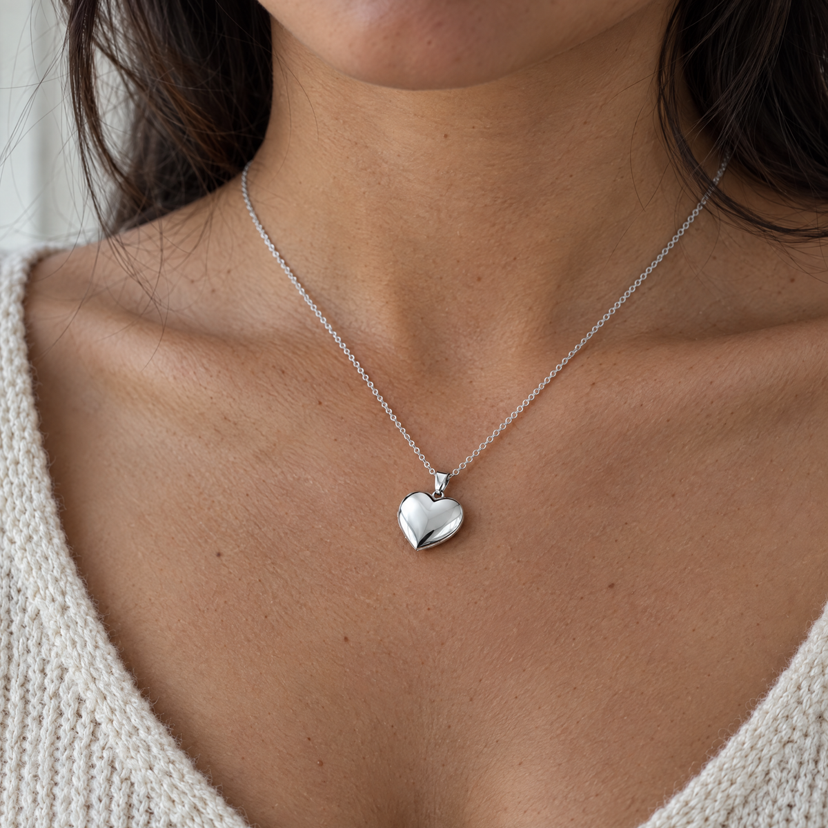 Cuello de una mujer con el collar de corazón plateado cerrado