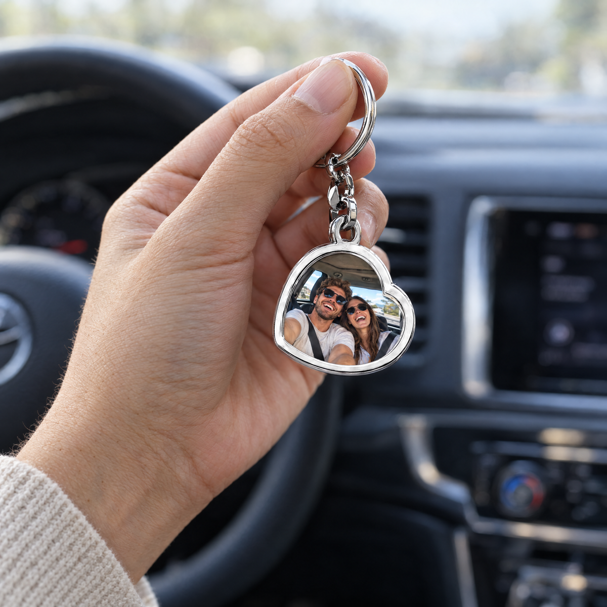 Mano sujetando el llavero de corazón con la foto de una pareja dentro de un coche