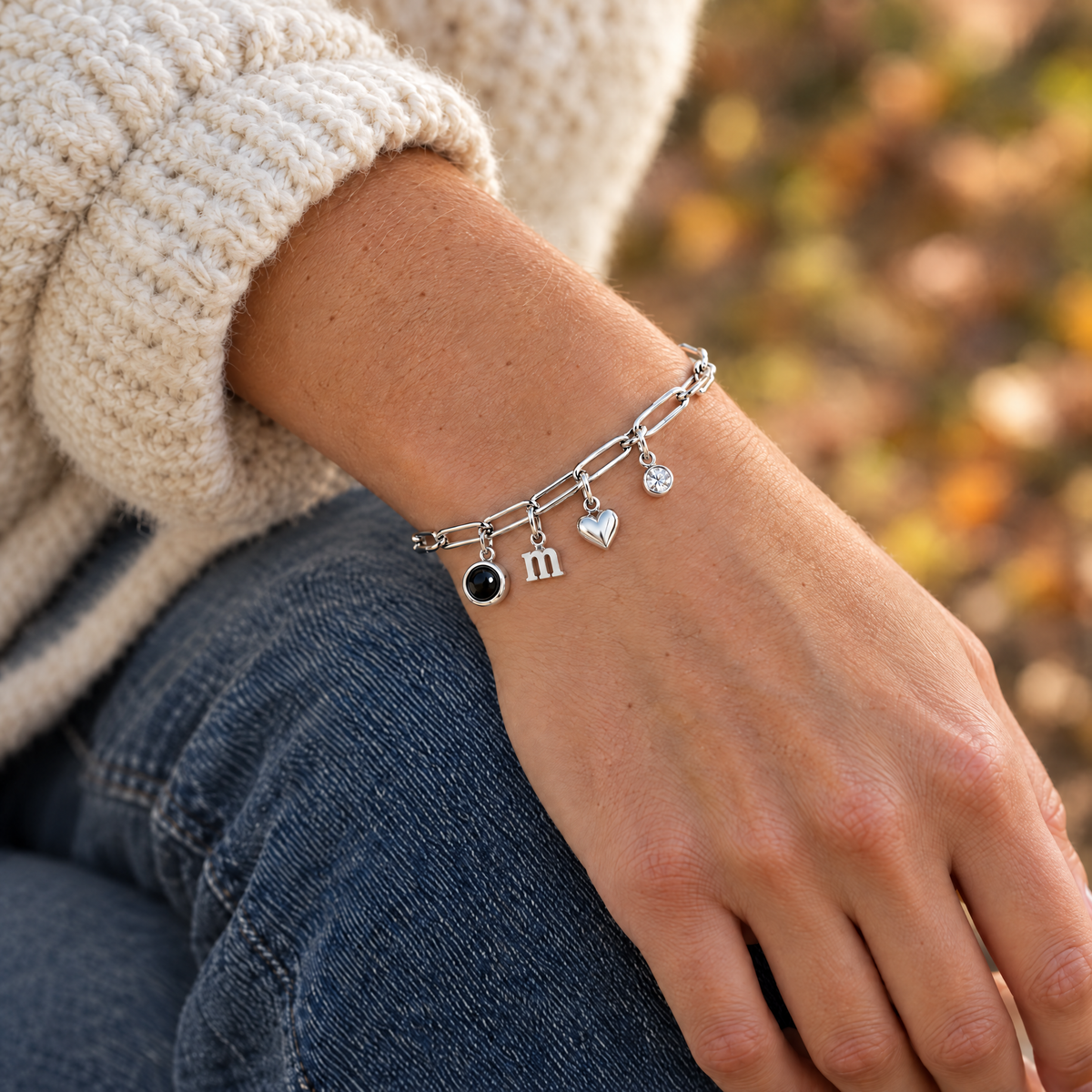 Mujer con la pulsera de charms plateada con foto, letra m, corazón y piedra